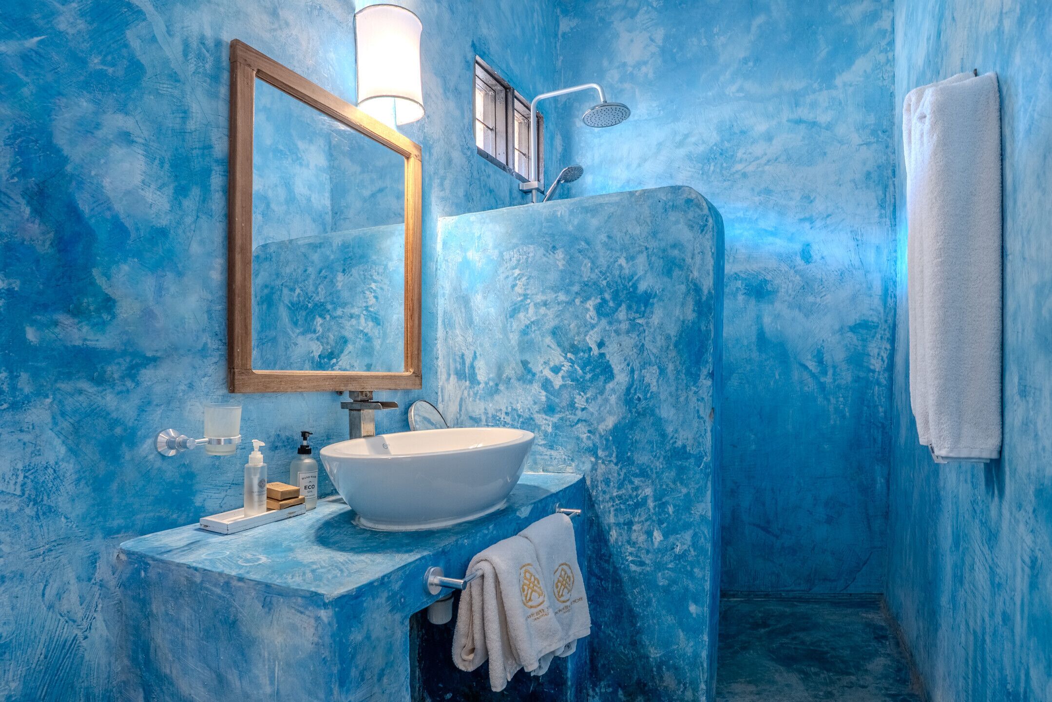 Un baño con lavamanos blanco, espejo y ducha.