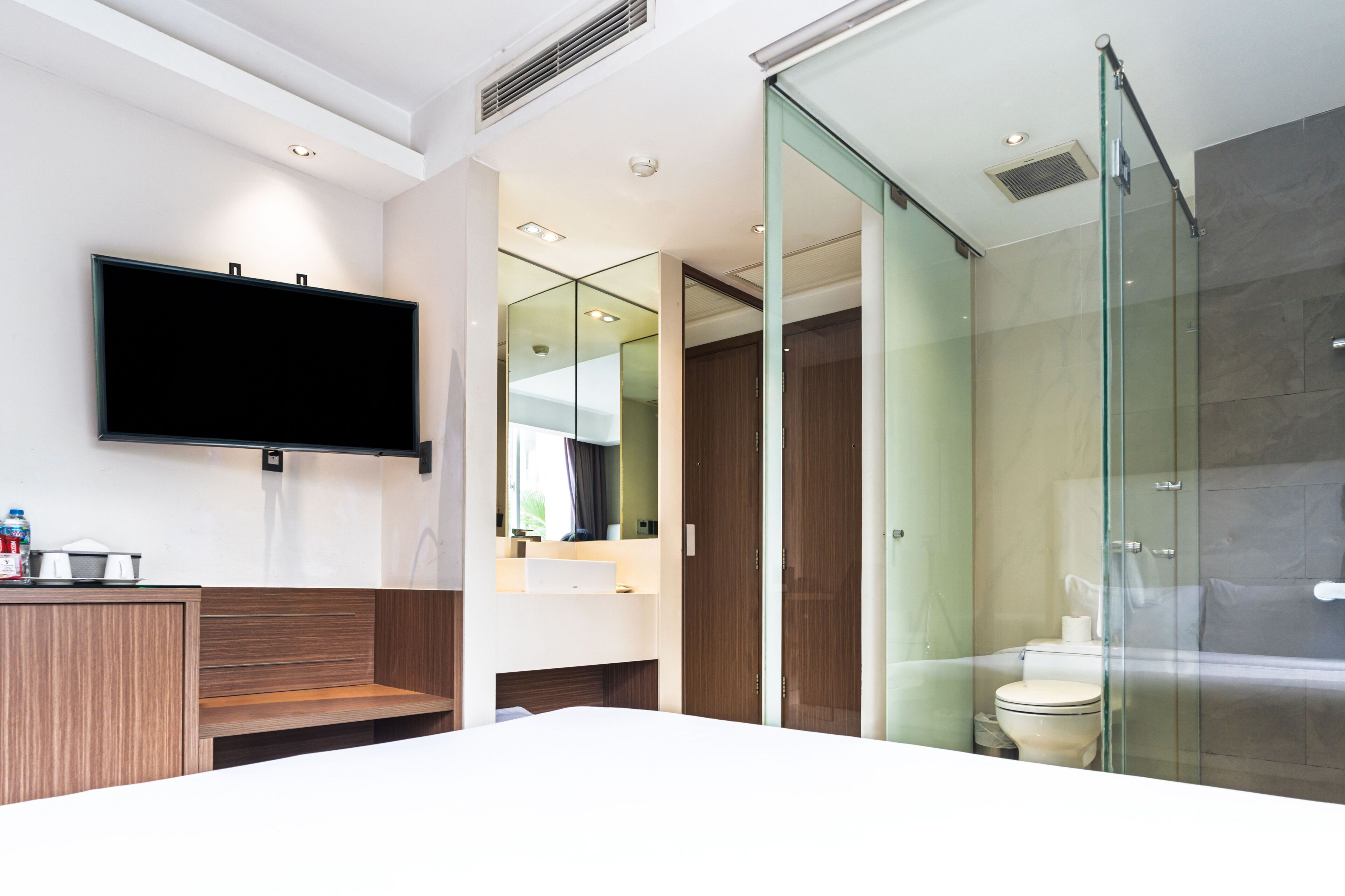A modern bathroom with a large mirror, a toilet, and a shower area.