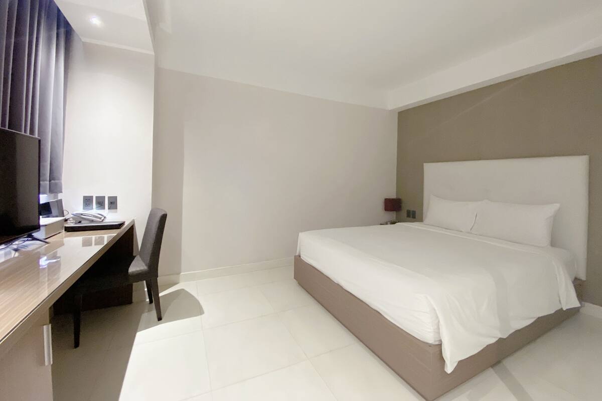 Une chambre d’hôtel moderne équipée d’un lit, d’un bureau, d’une chaise et d’un téléviseur.