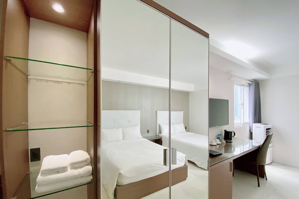 Une chambre d’hôtel moderne avec un grand lit, un bureau et une cloison en verre.