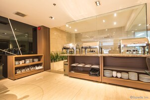 A modern restaurant with a buffet setup, including a wooden buffet counter and a glass partition.