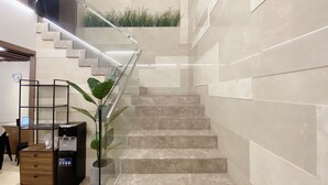 A modern staircase with glass railings, marble steps, and a wall-mounted planter with green plants. - Nicecy Ben Thanh Hotel (Ho Chi Minh City)