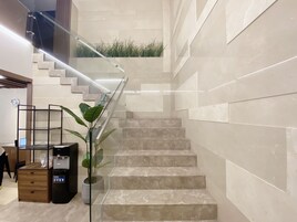 A modern staircase with glass railings, marble steps, and a wall-mounted planter with green plants.