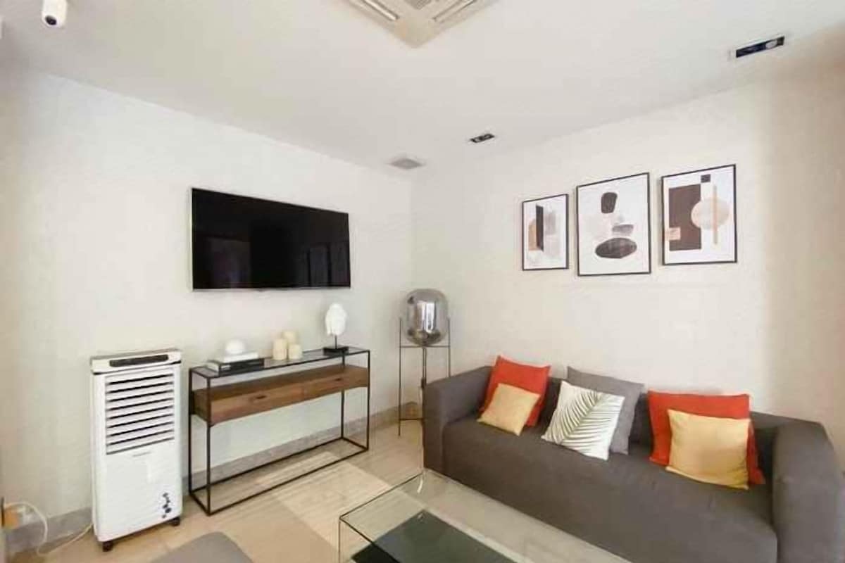 A living room with a sofa, a TV, a console table, and framed pictures on the wall.