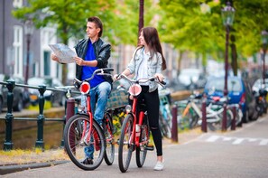 Two people on bicycles, one holding a map, on a city street with parked bikes and cars. - Nicecy Ben Thanh Hotel (Ho Chi Minh City)