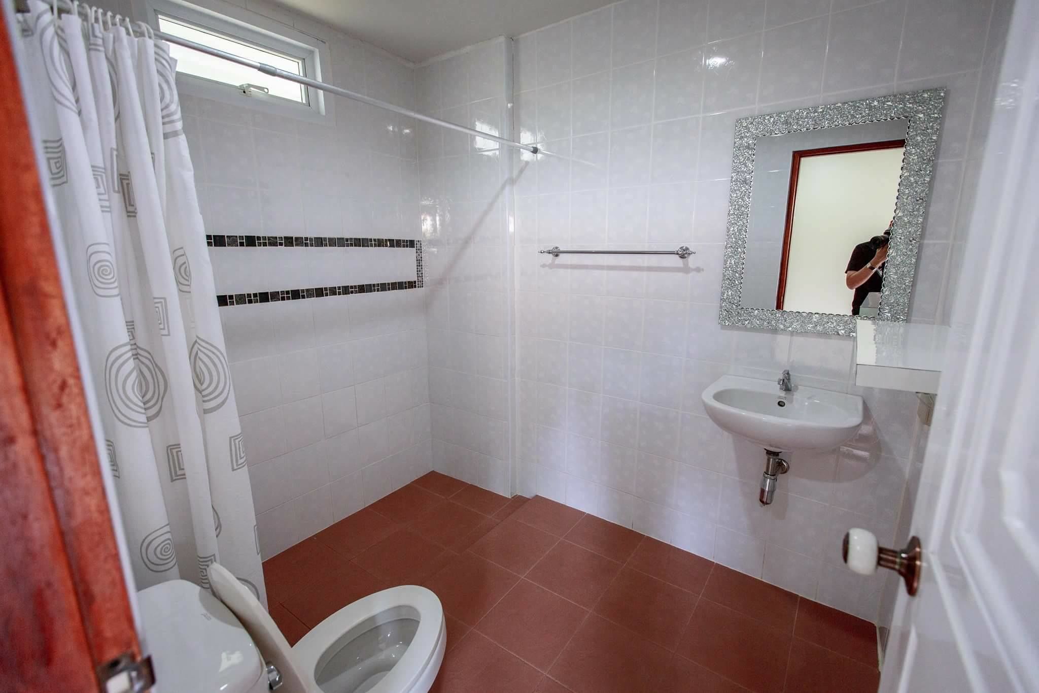 A bathroom with a toilet, shower, and sink.