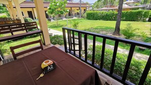 A table with a brown tablecloth and a keychain labeled "A2" on a balcony overlooking a well-maintained garden and residential buildings. - Ser-En-Dip-I-Ty (Ko Lanta)