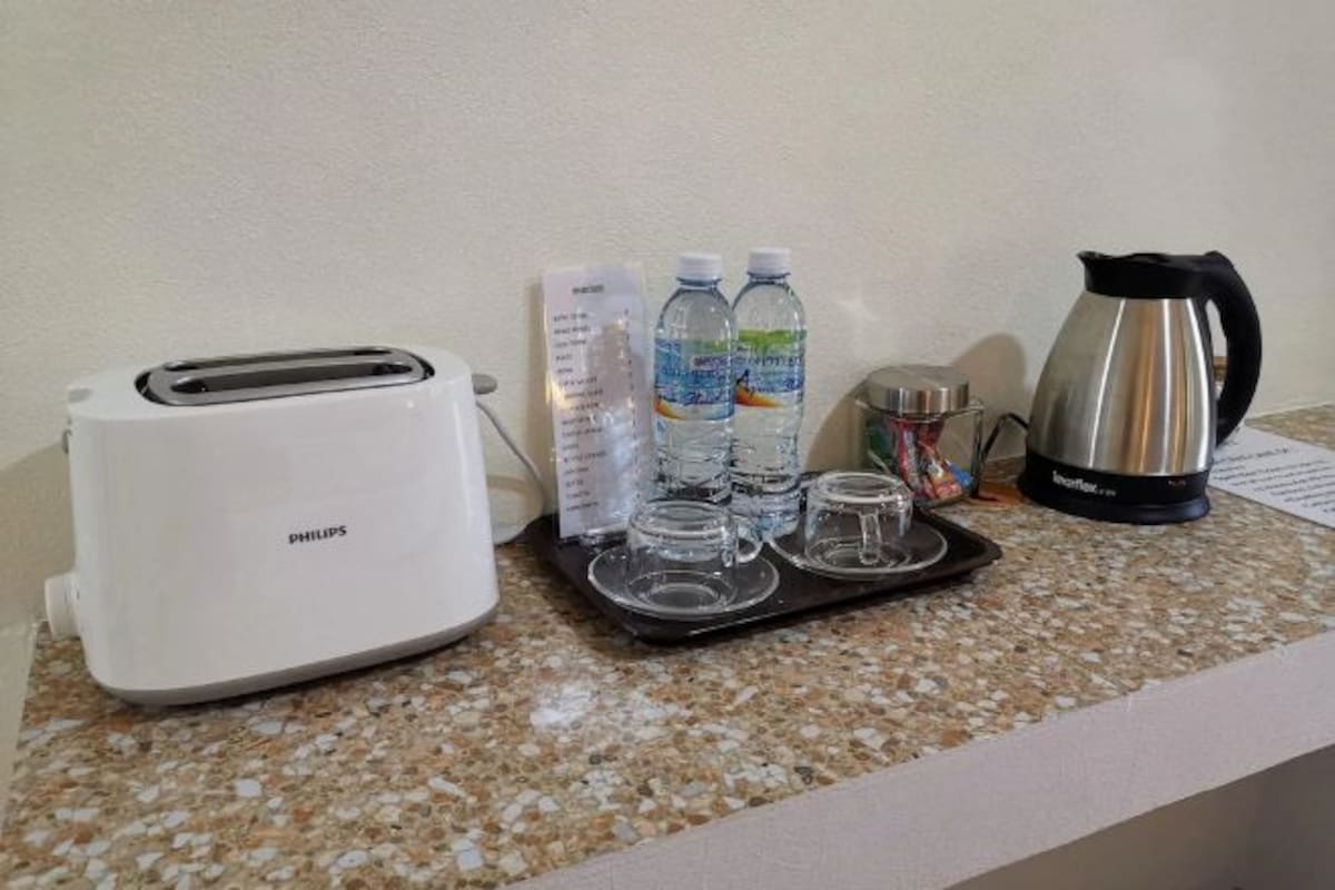 A kitchenette with a Philips toaster, a kettle, and two bottles of water on a granite countertop.