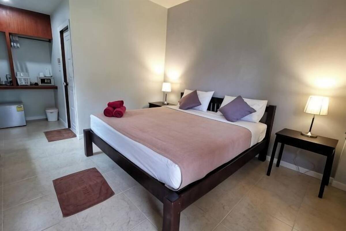 Una habitación de hotel con una cama, mesitas de noche, un escritorio y un espejo.