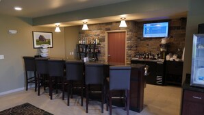 A bar area with a stone wall, a TV mounted on the wall, and a refrigerator. - Cobblestone Inn & Suites - Winterset, IA (Winterset)