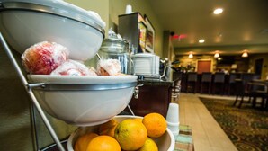 A buffet setup with a bowl of oranges and a container of fruit. - Cobblestone Inn & Suites - Winterset, IA (Winterset)