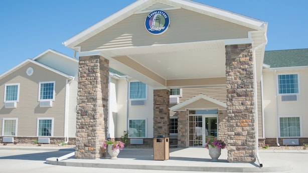A hotel entrance with a stone facade, a sign above the entrance, and a covered walkway. - Cobblestone Inn & Suites - Winterset, IA (Winterset)