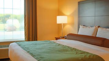 A hotel room with a bed, a nightstand, a lamp, and a window with curtains.