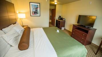 A hotel room with a bed, a television, a desk, and a framed picture on the wall.