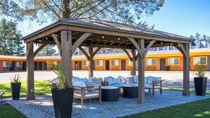 A covered outdoor seating area with wooden furniture and planters. - The Tide’s Out (Parksville)
