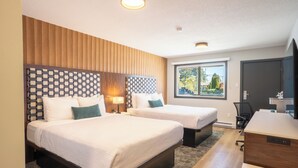A hotel room with two beds, a desk, and a window with a view of trees. - The Tide’s Out (Parksville)