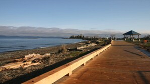 A wooden boardwalk along a lakeside with a gazebo and rocky shore. - The Tide’s Out (Parksville)