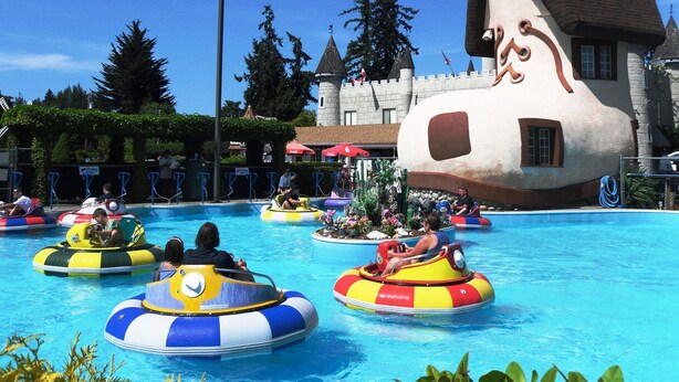 A pool area with water rides and a large building resembling a house. - The Tide’s Out (Parksville)