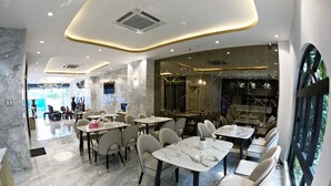Un interior de restaurante moderno con suelo de mármol, mobiliario contemporáneo y vistas al exterior.