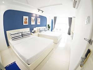 Une chambre d’hôtel moderne avec deux lits, un mur d’accent bleu et des œuvres d’art.
