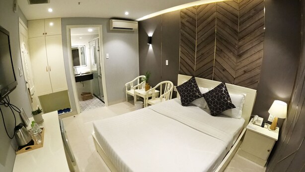 Una habitación de hotel moderna con una cama grande, una mesita de noche y un pequeño escritorio con silla.