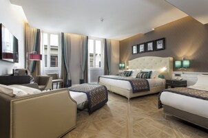 A hotel room with two beds, a desk, a chair, and a television.