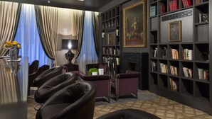 A modern living room with a fireplace, bookshelves, and leather chairs.