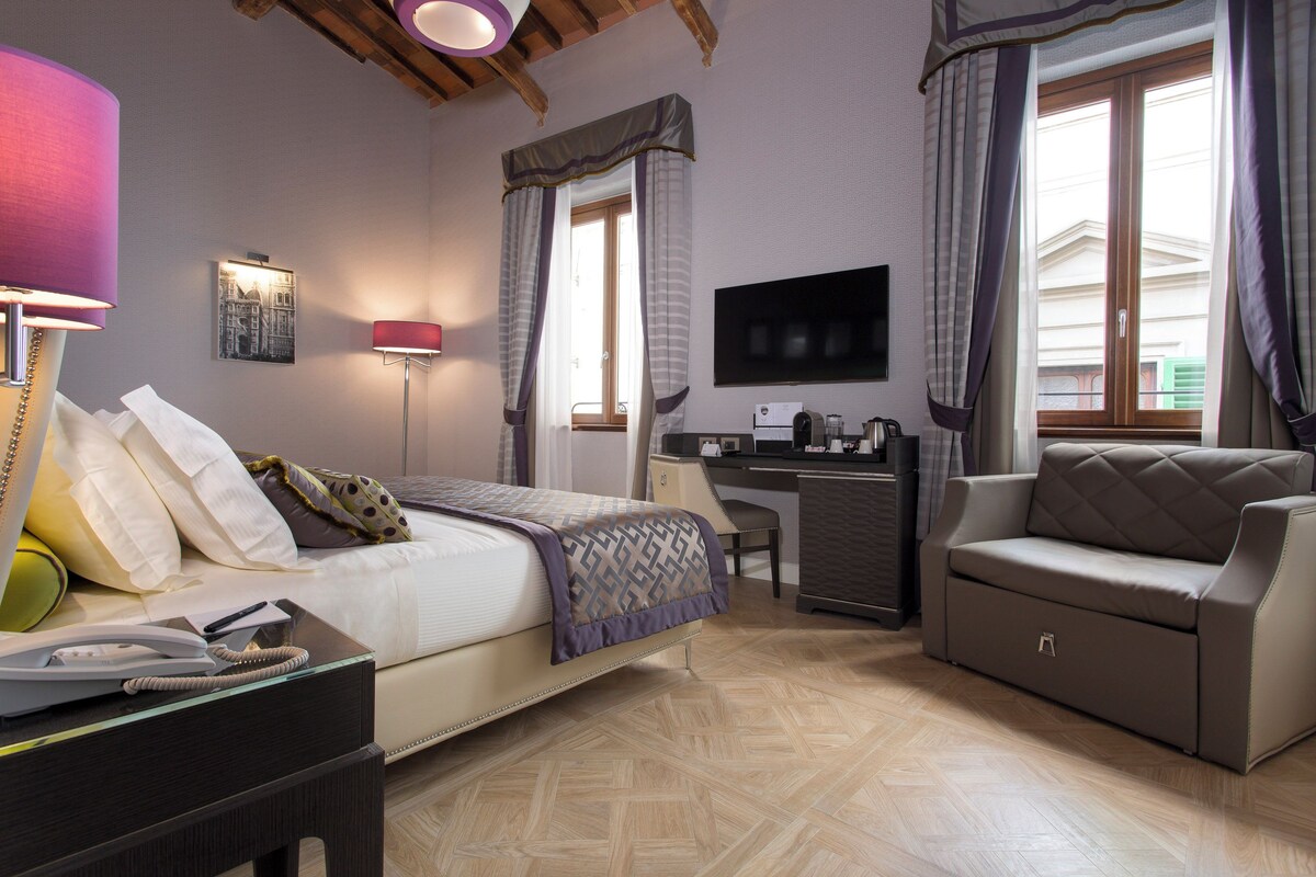 Une chambre d’hôtel avec un lit, un bureau, un canapé et une télévision.