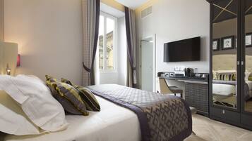 Quarto de hotel com cama, escrivaninha, televisão e guarda-roupa.