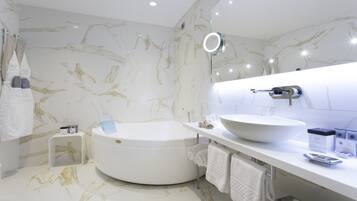 A modern bathroom with a round bathtub, a large sink, and a mirror with integrated lighting.