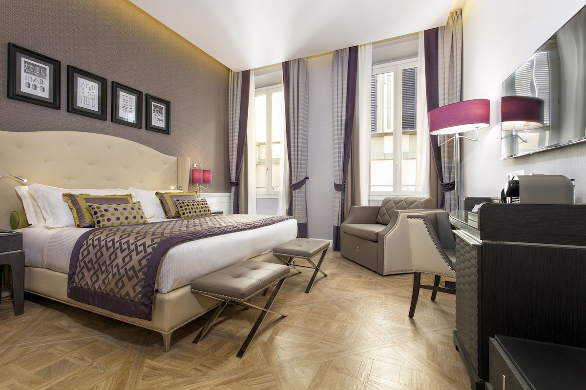 Habitación de hotel con una cama grande, un escritorio, una silla y vistas a la ciudad.
