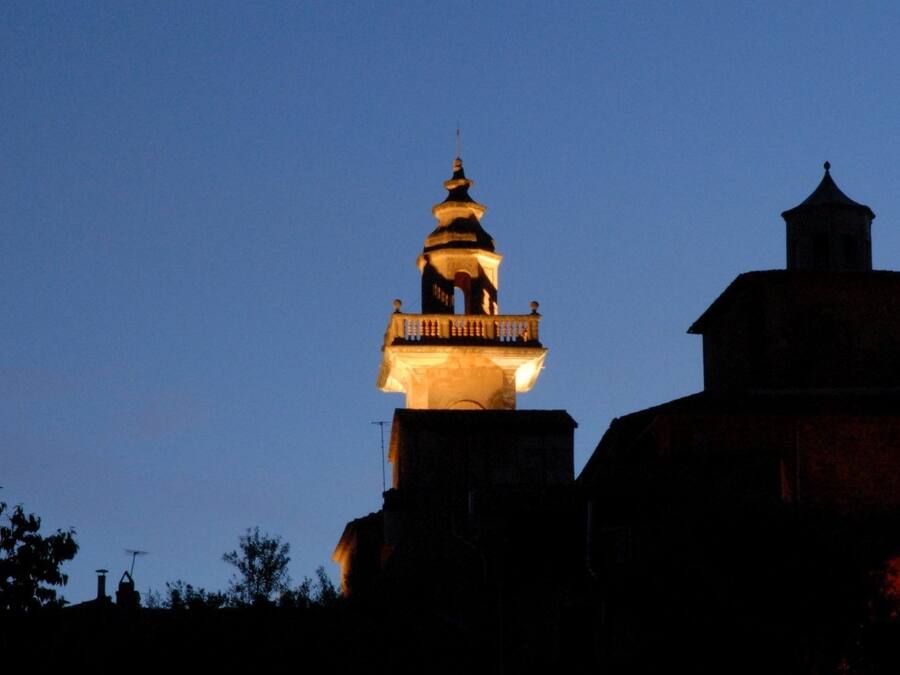 En byggnad med ett markant torn och en kupol, upplyst av artificiell belysning mot en skymningsfärgad himmel.