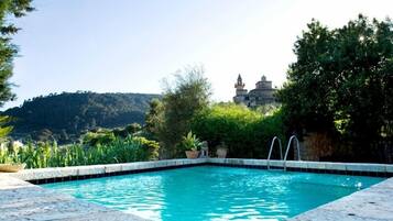 Una piscina al aire libre, sombrillas, sillones reclinables de piscina
