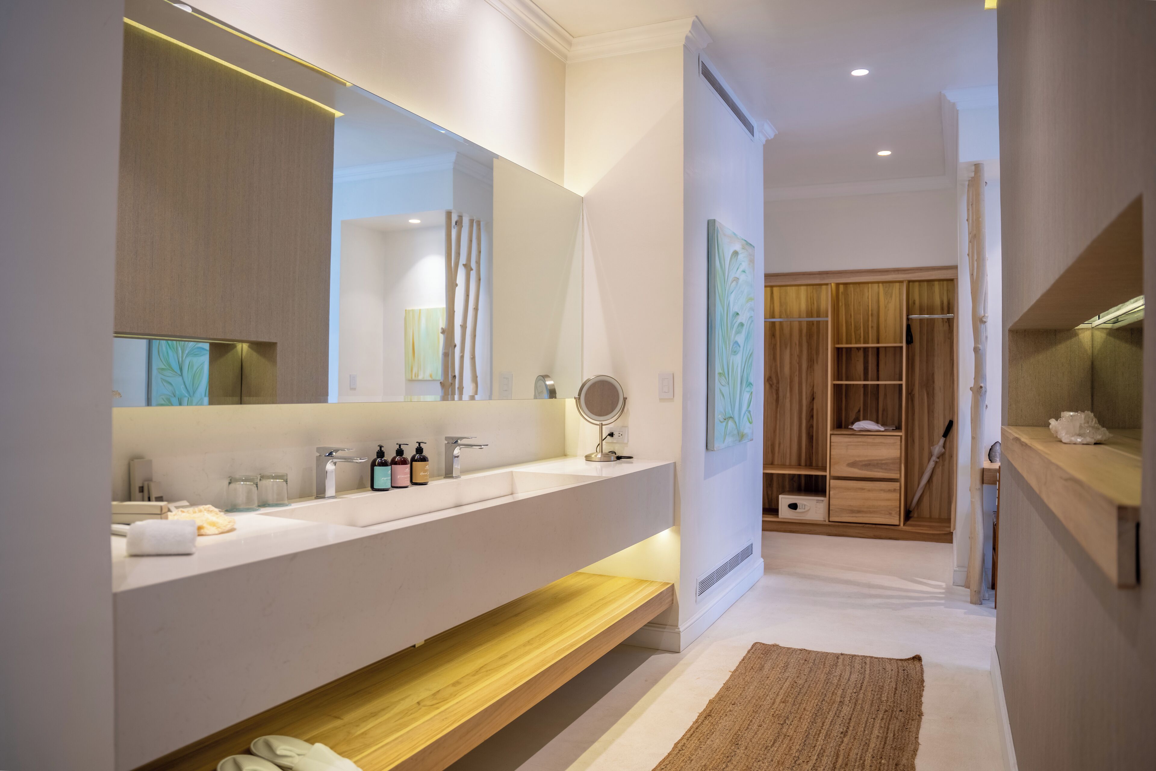A modern bathroom with a large mirror, white sink, and wooden vanity.