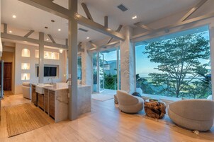 Uma cozinha moderna com uma ilha central, uma janela ampla com vista e um espaço de estar aconchegante com uma mesa de centro de madeira peculiar.