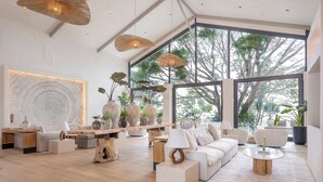Un salón amplio con un ventanal grande, suelo de madera y muebles modernos.