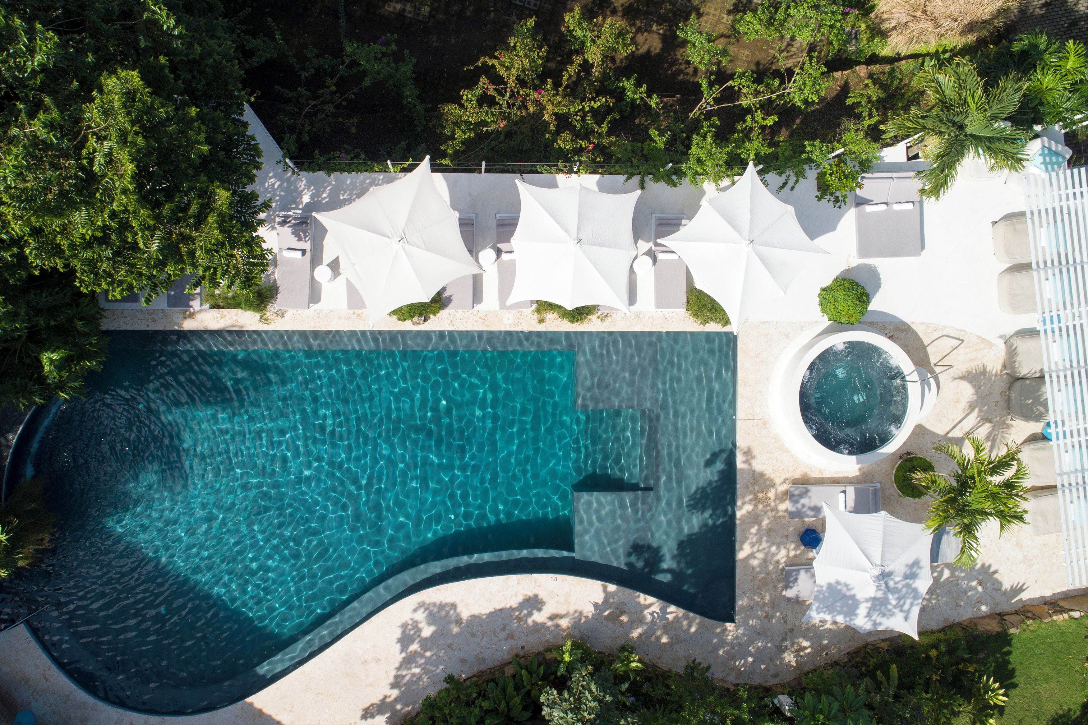 Vista aérea de un resort con piscina, tumbonas y jacuzzi.
