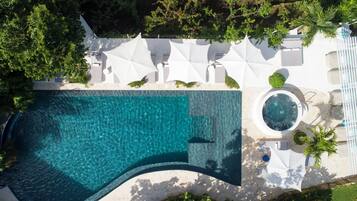 Vista aérea de un resort con piscina, tumbonas y jacuzzi.