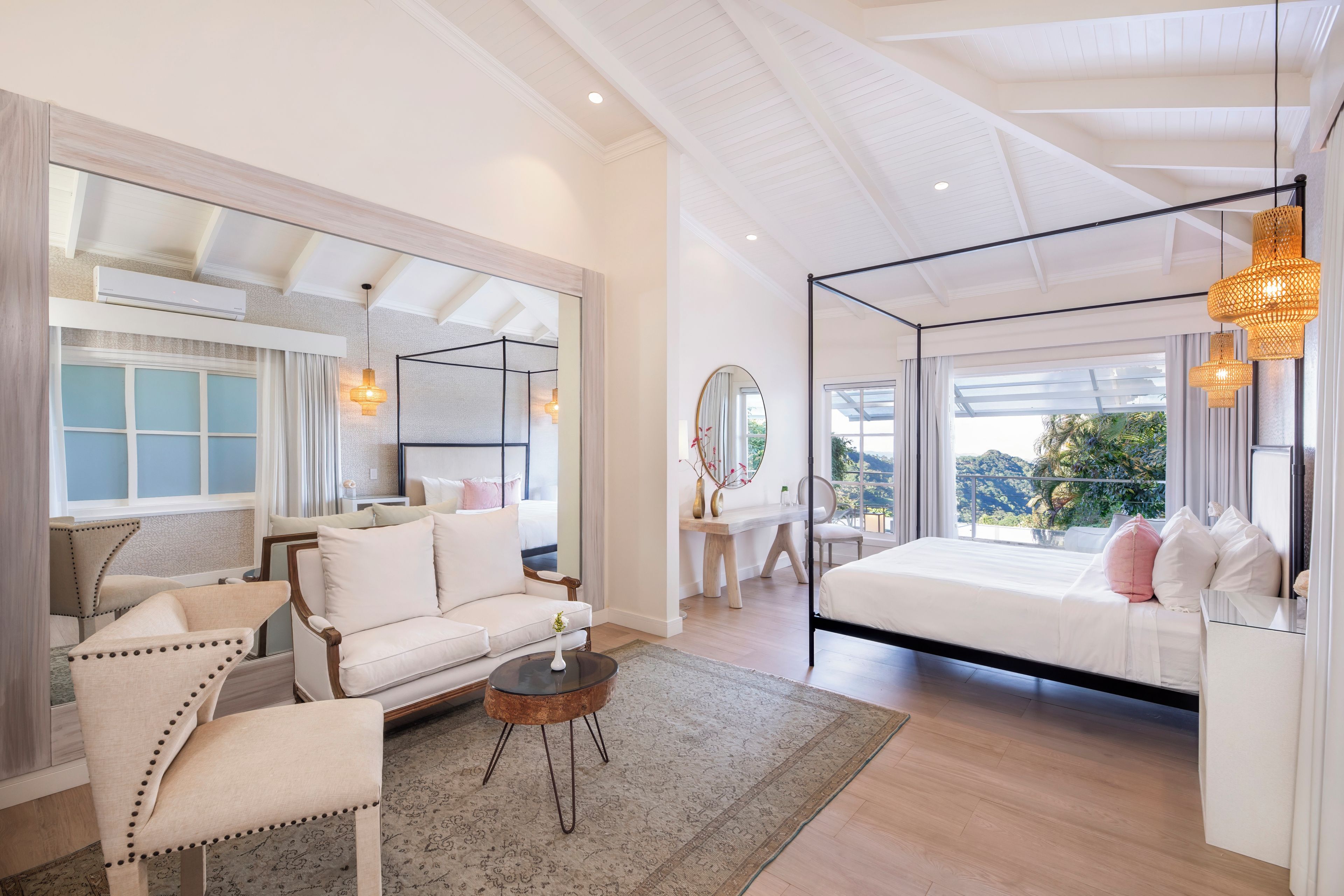 A spacious bedroom with a large bed, a sitting area with a sofa and chairs, and a view of the outdoors.