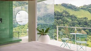 Un dormitorio con un ventanal grande que da a un paisaje verde y exuberante.