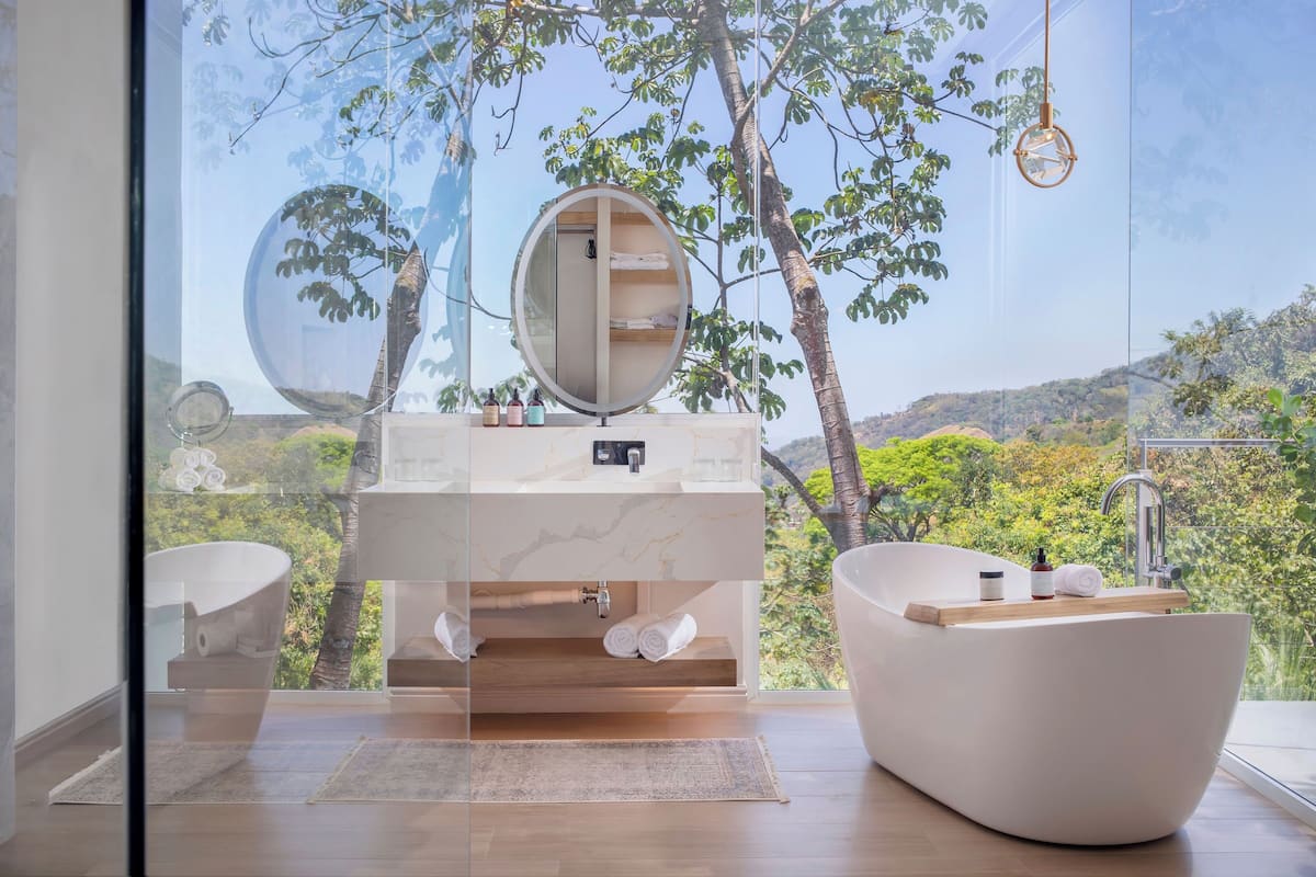 A modern bathroom with a freestanding bathtub, a large mirror, and a sink with a marble countertop.
