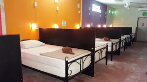 Una habitación de hotel con una cama individual, cabecera y lámpara fijada a la pared.