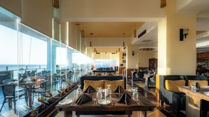 Un restaurante moderno con techo alto, amplios ventanales y un área de comedor central con mesas listas para el servicio.