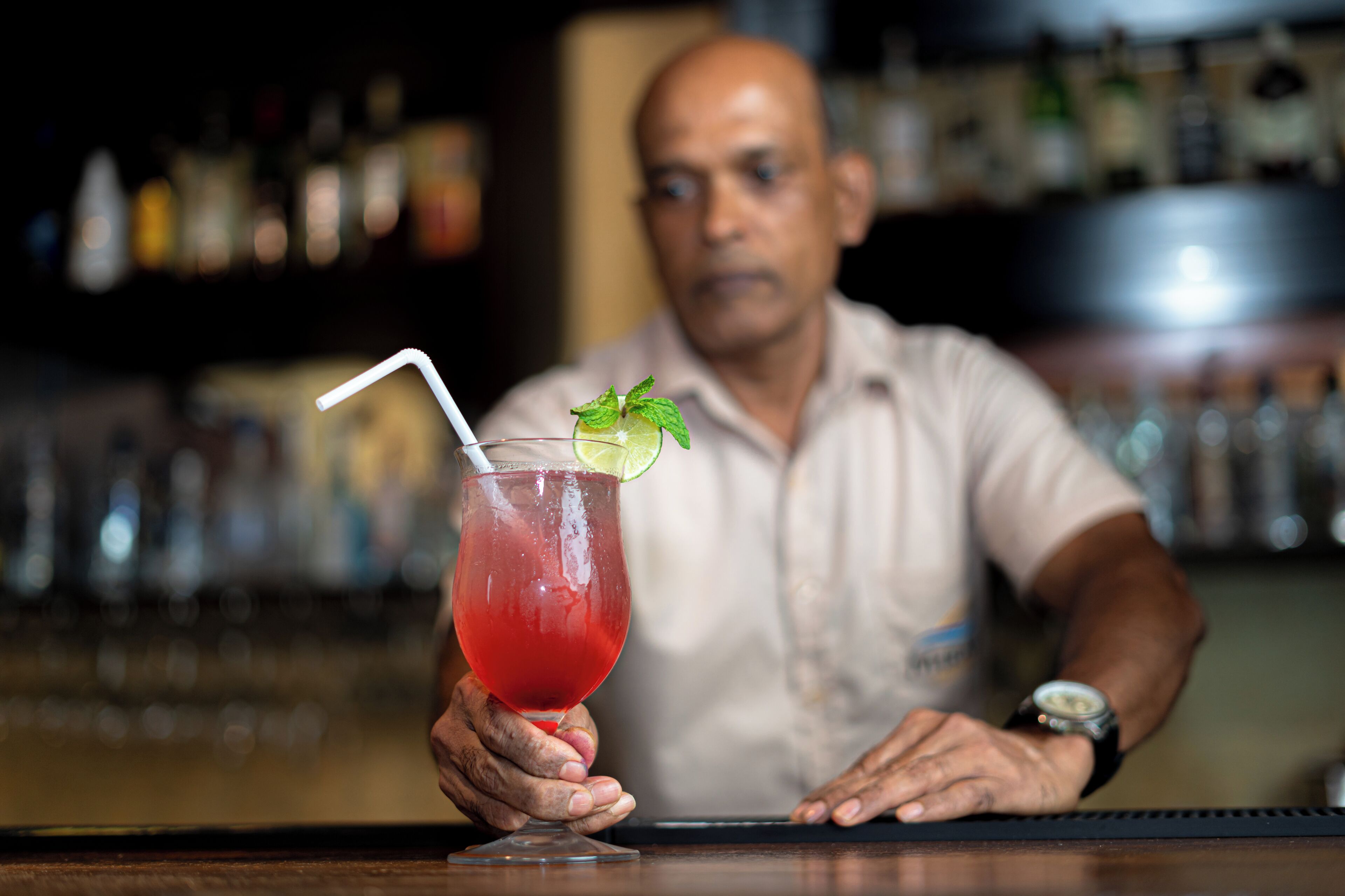 A bartender holding a cocktail with a lime garnish.