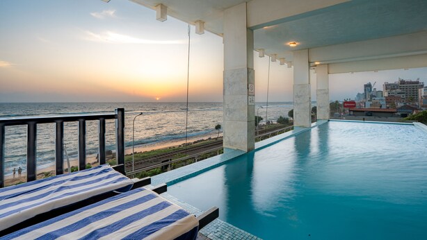 Una piscina con vistas al océano y un paisaje urbano al fondo.