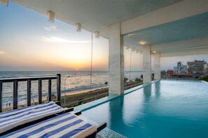 A swimming pool with a view of the ocean and a cityscape in the background.