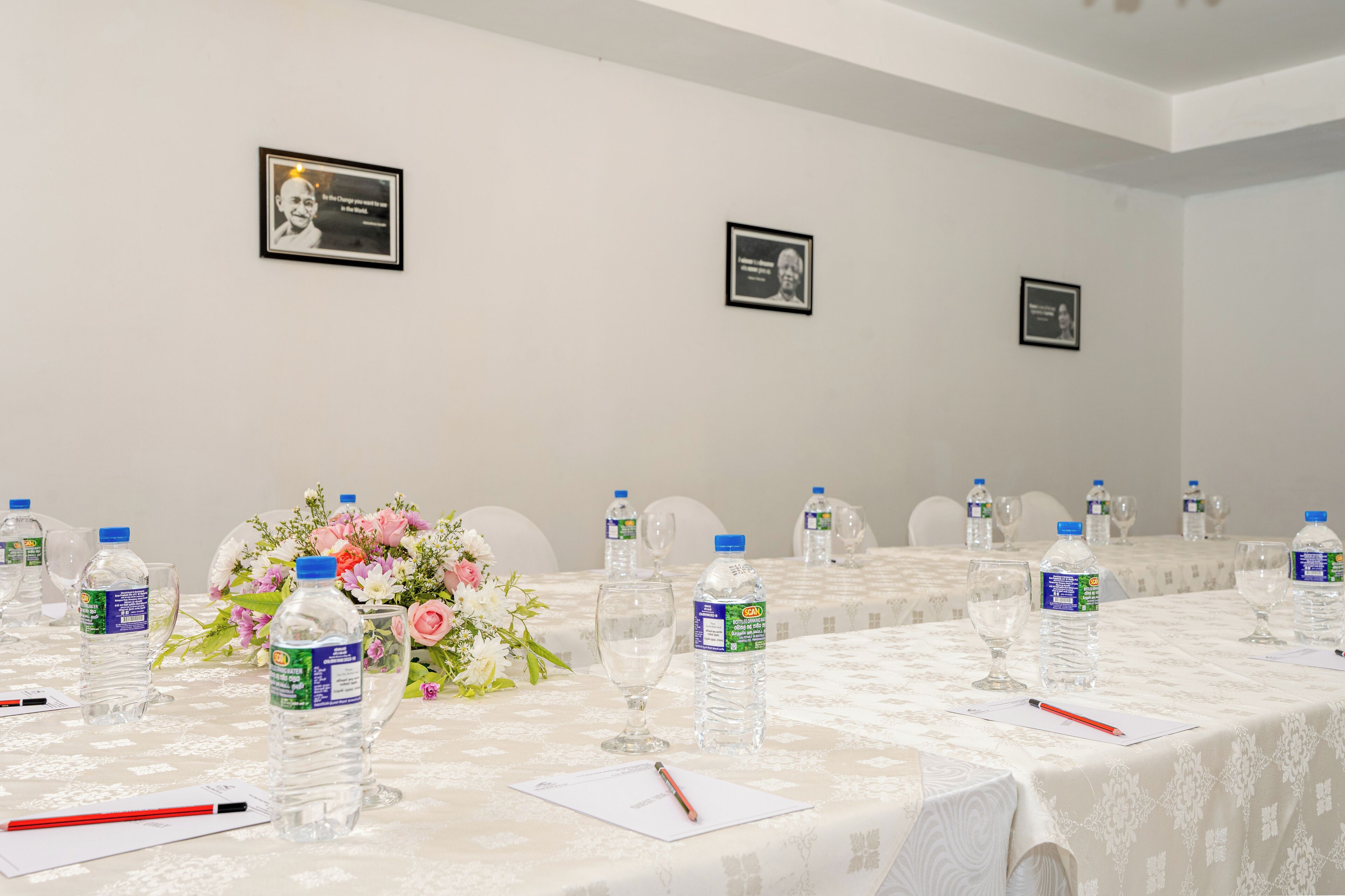 A conference room with a long table, water bottles, glasses, and a floral centerpiece.