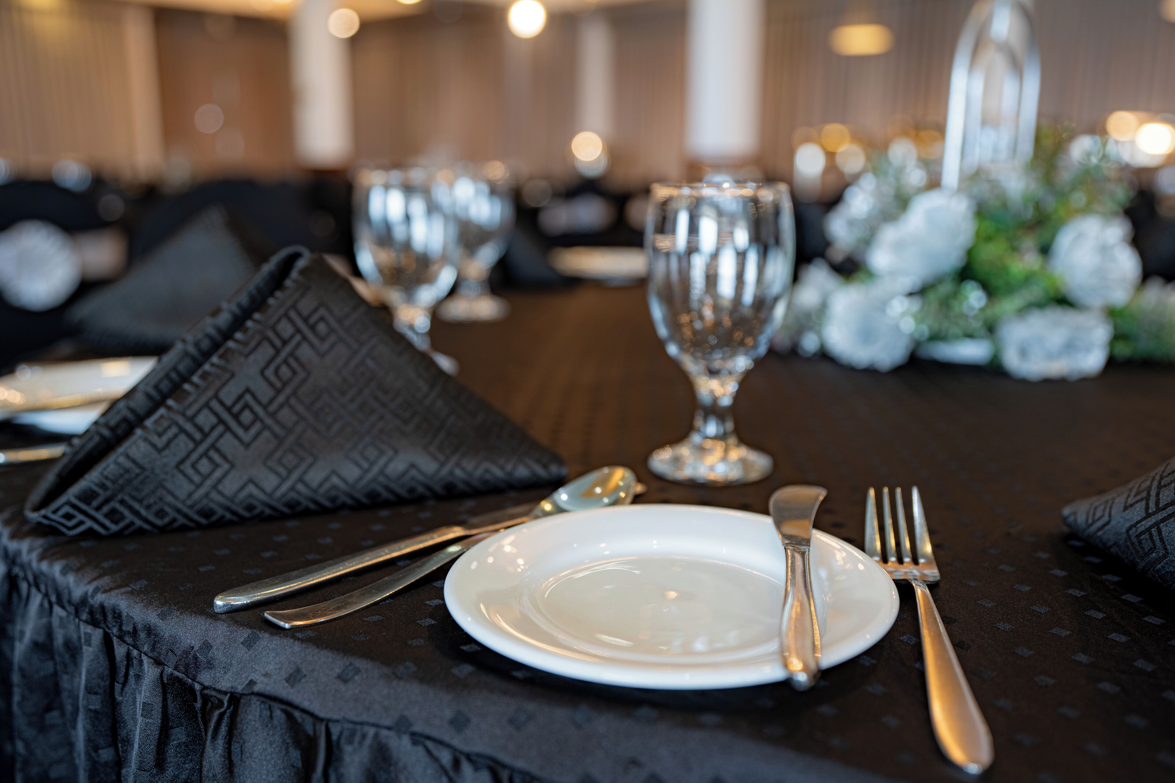 A dining table set with a white plate, silverware, and a glass.