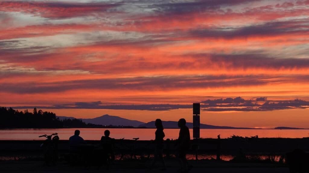 A sunset with silhouettes of people and a mountain in the background.