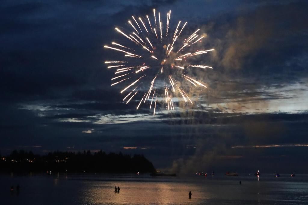 A nighttime scene with a large firework display over a body of water.